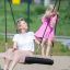 Donna e bambino su una Single Swing BNS 90cm in un’area giochi.