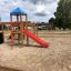 Struttura da parco giochi in legno Climbing Booth con tetto blu, scivolo rosso e elementi per arrampicarsi in un san