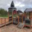 Campanille playground castle con scivoli e elementi per arrampicata in un parco.