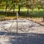 Struttura a piramide con rete da arrampicata in un parco giochi circondato da alberi.