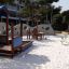 Attrezzature da parco giochi, incluso Clover Table, in un'area esterna sabbiosa.