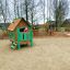 Bambini che giocano su Britta's Playhouse struttura da gioco in legno con parete da arrampicata e scivolo.