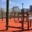 Spillikins wooden playhouse in un'area giochi all'aperto con pavimentazione di sicurezza rossa e edifici urbani circostanti
