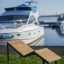 Saint-Tropez Deck Chair sull'erba vicino a yacht di lusso in un porto turistico.