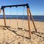 Double Safety Seat double swing posizionato su una spiaggia sabbiosa in riva al mare