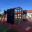 Climbing Booth Nature, wooden playhouse con pareti da arrampicata e scivolo in un parco giochi.