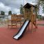 Triangle Modern Nature wooden playhouse with slide sul parco giochi