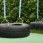 Wooden Tire double swing con pneumatici neri e corde blu in un parco giochi