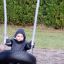 Bambino seduto su un Wooden Tire double swing in un parco giochi.