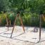 Triple swing in un parco giochi con sabbia.