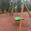 Verde Swing Seat GBNS su una struttura in legno per parco giochi in un parco.