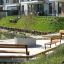 Area di seduta del parco con Ryga Bench w/ Backrest e altre panchine in un contesto residenziale moderno