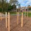 Stazione fitness all'aperto Bars I con elementi in legno e metallo in un parco.