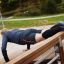 Uomo che si allena su una panca per sit-up all'aperto in una giornata di sole.