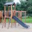Struttura da gioco in legno Romping Cottage con scivolo e rete da arrampicata.