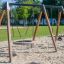 Swing Frame 1(BNS) +1 (double swing) su un parco giochi sabbioso con un sedile circolare.