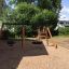 Attrezzatura da parco giochi Swing Frame 1(BNS) +1 (double swing) in un cortile con sabbia e alberi verdi.