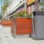 Chicago bin accanto a una grande fioriera in legno su un marciapiede cittadino.
