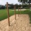 Struttura in legno Rope Bar in un parco giochi con erba e sabbia tutt'intorno.