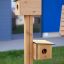 Bird feeder con due casette per uccelli in legno montate su un palo verticale.