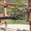 Casetta da gioco in legno Sonora con travi in legno e ponte di rete in un parco giochi all'aperto.