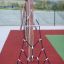Ural climbing net in un allestimento di parco giochi con supporti in legno e pavimentazione di sicurezza rossa.