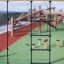 Ural climbing net in un parco giochi all'aperto con strutture in legno sullo sfondo.
