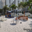 Villa sandbox with a playhouse in un moderno parco giochi con alberi ed edifici sullo sfondo.