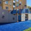Nave a vapore per area giochi con scivolo su superficie in gomma blu in una zona residenziale.