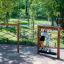 Bambini che giocano su attrezzature da parco giochi in legno per arrampicarsi ed equilibrarsi Trim Trail Nature II in un p