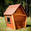 Casetta in legno Crooked House su un campo erboso.