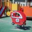 Attrezzatura da parco giochi rossa Copter rocking con area giochi e scivolo sullo sfondo.