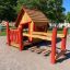 Casetta da gioco in legno con dettagli rossi in un parco giochi.