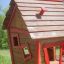 Casetta da gioco in legno con finiture rosse in un'area erbosa - Anna's Playhouse.