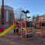 Jungle castle with slide in un parco giochi con altre attrezzature da gioco e edifici sullo sfondo.