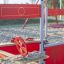 Attrezzatura da parco giochi Jupiter con volante rosso in un'area giochi sabbiosa