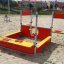 Attrezzatura da parco giochi Jupiter in rosso e giallo sulla sabbia.