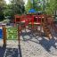 Set da gioco per bambini Race Track Board con scivoli e strutture per arrampicarsi in un parco.