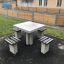 Tavolo in cemento da esterno Ludo con quattro sedute integrate in un parco.
