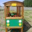 Struttura da parco giochi in legno a forma di autobus con dettagli verdi e gialli.