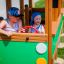 I bambini giocano in una struttura Bus in legno in un parco giochi.