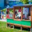Bambini che giocano in una struttura da parco giochi in legno a forma di autobus.