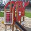 Attrezzatura da gioco a tema Helicopter rossa su un parco giochi sabbioso.