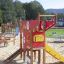 Struttura da gioco colorata chiamata Helicopter con scivolo ed elementi di arrampicata in un parco.