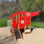 Struttura da gioco per bambini Helicopter rossa e gialla con scivolo e elementi di arrampicata in un parco