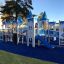 Area giochi a tema Winter Mansion con strutture del castello blu e bianche, scivoli ed elemento da arrampicata
