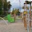 El Dorado wooden playhouse con elementi di arrampicata e accenti verdi in un contesto di parco giochi.