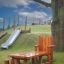 Set Table Nature with a Chair and Stools in legno sull'erba del parco giochi vicino a un albero e a uno scivolo