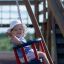 Un bambino che si diverte su Baby Single Swing in un parco giochi.