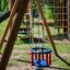 Double Baby Swing in un parco giochi colorato con struttura in legno.